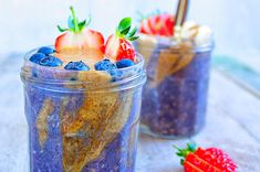 two mason jars filled with blueberries, strawberries and granola