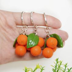 four oranges with green leaves on them are being held by a hand