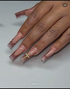 a woman's hand with long, shiny nails and a gold cross on it