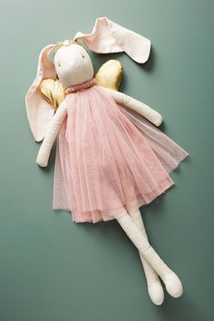 a stuffed animal in a pink dress laying on top of a green surface