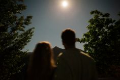 a man and woman are looking at the moon