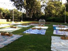 several picnic blankets laid out on the grass in front of an outdoor dining table and seating area