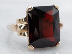 The garnet in this show-stopping statement ring is a deep crimson hue with electric flashes of cherry red sparkling from within. The emerald cut of the gemstone is a nice twist on traditional cocktail rings. With its high profile and sleek design, this ring commands attention!Metal: 10K Yellow GoldGem: Pyrope Garnet 10.40 CaratsGem Measurements: 10.6 x 13.3 mm, Emerald CutRing Size: 5Marks: "10K" Stamped on the inside band Mens Ruby Ring, Gold Garnet Ring, Amethyst Cocktail Ring, Pyrope Garnet, Emerald Cut Rings, Tanzanite Diamond, Gold Cocktail Ring, Purple Sapphire, Garnet Jewelry