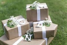 three wrapped presents sitting on top of each other in front of some grass and flowers