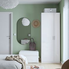 a bedroom with green walls, white furniture and a large round mirror on the wall