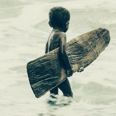 a young boy holding a surfboard in the ocean