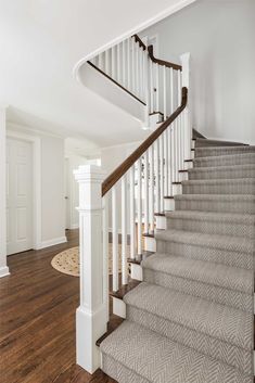 a white staircase with wood handrails and carpet