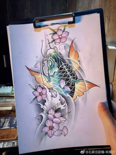 a drawing of a fish and flowers on a piece of paper in someone's hand