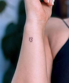 a woman's wrist tattoo with the number thirteen on it