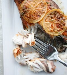 a white plate topped with fish and lemon slices