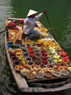 a man in a boat filled with lots of food on top of the water,