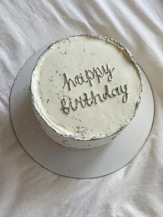 a birthday cake with the words happy birthday written on it sitting on a white tablecloth