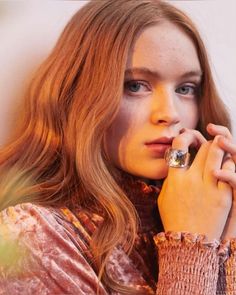 a close up of a person with long hair holding a ring in her hand and looking at the camera