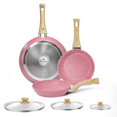 pink ceramic cookware set with wooden handles and matching pots, pans and spatulas