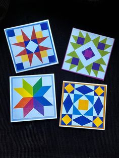 four different colored quilts on a black tablecloth with one star in the middle