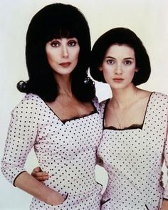 two women standing next to each other in front of a white wall with polka dots