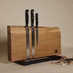 three knives in a wooden box with scissors on the bottom and one knife sticking out of it's side