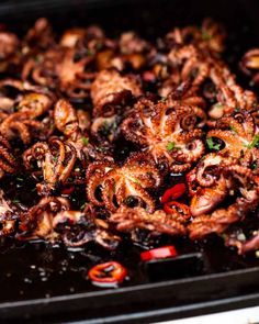 an octopus dish is being prepared on a grill with peppers and onions in the foreground