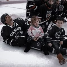 a group of young children sitting on top of an ice rink next to each other