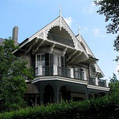 an ornate house with balconies on the second floor and balconyes is surrounded by greenery