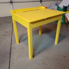 a yellow table sitting on top of a cement floor