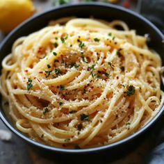 a black bowl filled with pasta and parmesan sprinkled on top of it