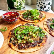 three small pizzas are sitting on a cutting board next to some condiments