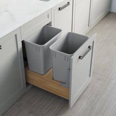 two grey trash cans sitting in the middle of a kitchen