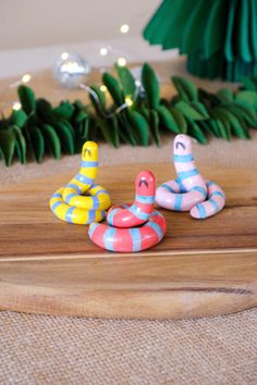 three rubber toy snakes sitting on top of a wooden board next to christmas trees and lights