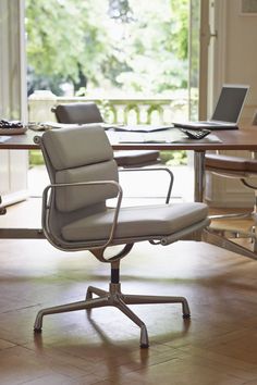 an office chair sitting in front of a laptop computer on top of a wooden table