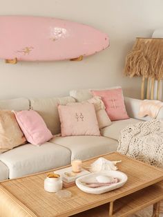 a living room with a couch, coffee table and surfboard on the wall above it