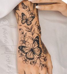 a woman's hand with tattoos on it and butterflies flying around the wrist area