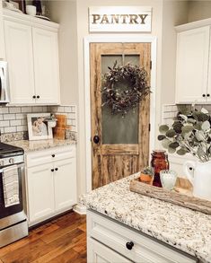 a kitchen with white cabinets and an old door in the center is featured on instagram