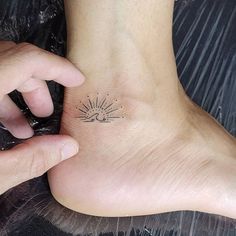 a person's foot with a small sun tattoo on the left side of their ankle