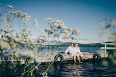 two people sitting on a dock in the water