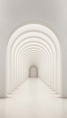 an empty tunnel with white walls and arches leading to the light at the end is seen in this image