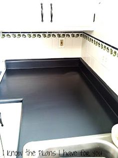 an empty kitchen with black counter tops and white cabinets