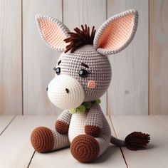 a crocheted donkey sitting on top of a wooden floor