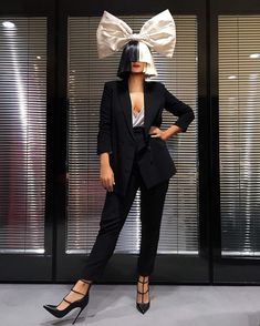 a mannequin dressed in black and white with a bow on her head, standing next to glass doors