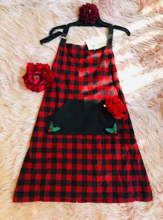 a red and black checkered dress with flowers on the side, sitting on a fur rug