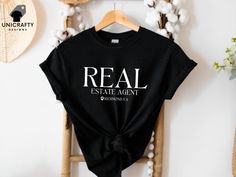 Elevate your real estate game with our Custom Real Estate Agent T-shirt. This personalized real estate tee, featuring your custom location, is the perfect gift for any dedicated realtor. Ideal for agent marketing attire, it combines professionalism and style, making it a must-have for your wardrobe. See more of our designs in our REAL ESTATE section: https://www.etsy.com/shop/unicraftydesigns/?etsrc=sdt&section_id=49847464 CHECK OUT MORE FOR OUR UNIQUE DESIGNS: unicraftydesigns.etsy.com SIZE & MATERIAL * Unisex T-shirt * Runs true to size * 100% cotton (fibre content may vary for different colours) HOW TO ORDER: *Please make sure to check all photos in the listing. *Choose your shirt colour and size. *Click add to cart. You can follow the same steps to add more items in your cart. *Click " Real Estate Shirts, Shirt Colour, Realtor Gifts, Baseball Shirts, Estate Agent, Real Estate Agent, Custom Shirts, Shirt Design, Unisex T Shirt