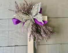 a purple and silver boutonniere on a wooden cross