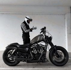 a man wearing a helmet is standing next to a black and silver motorcycle in an empty garage