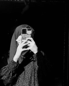 a woman taking a selfie with her cell phone in front of her head and wearing a hijab