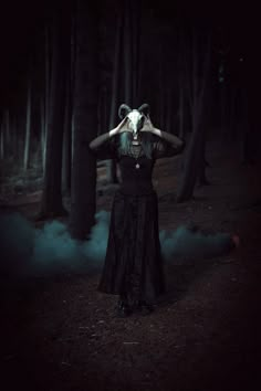 a woman in a dark forest with her hands on her head