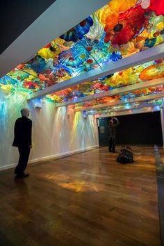 a man standing in front of a ceiling with colorful glass flowers on it's ceiling