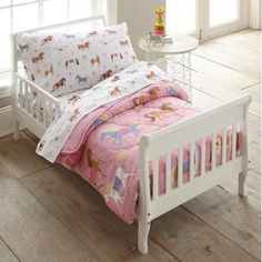 a small child's bed with pink sheets and unicorns on the sheet set