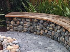 a bench made out of rocks sitting on top of a stone walkway next to plants