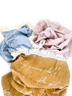 four scarves with writing on them sitting next to each other in front of a white background