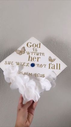 someone is holding up a graduation cap that says god is within her she will not fall